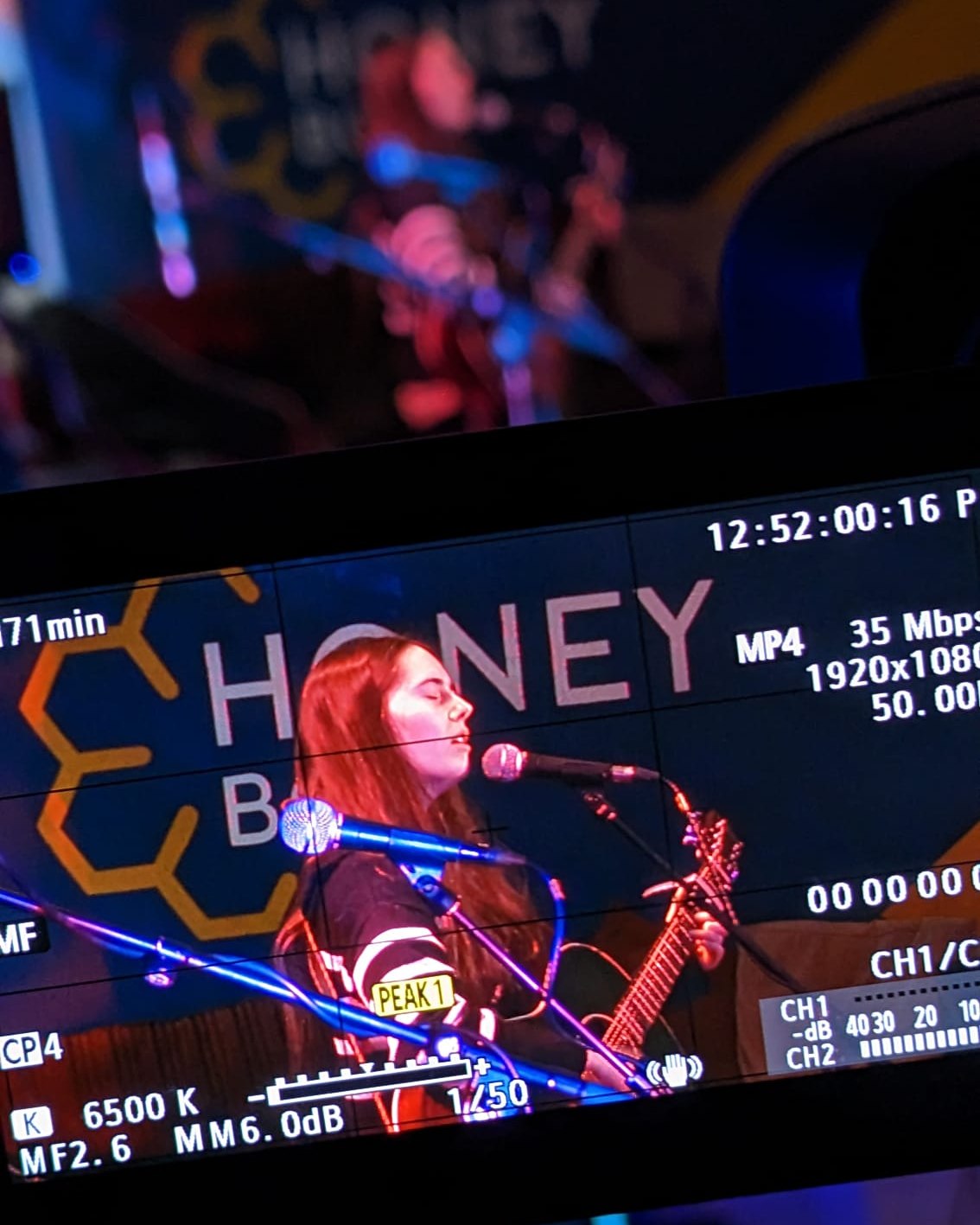 band preforming on stage with pink lighting shot through a screen of a camera